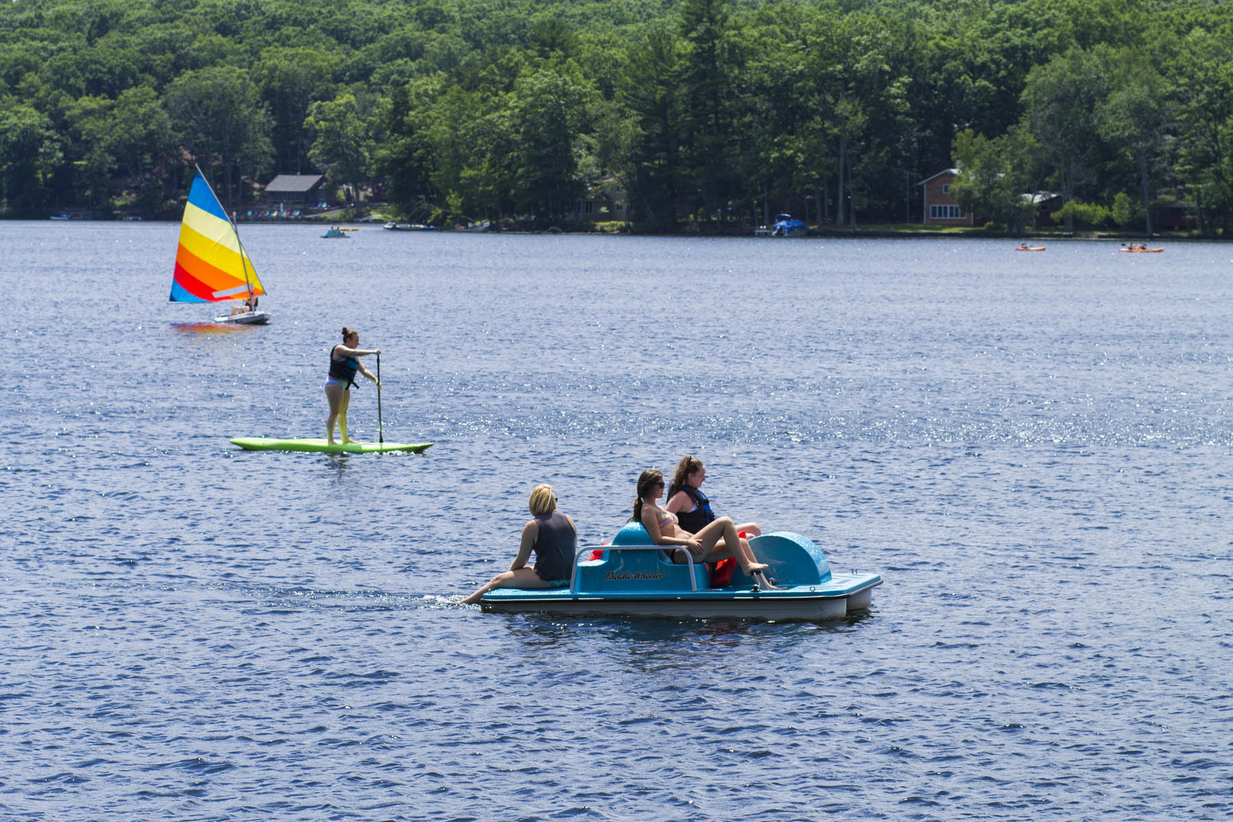 Guests in a dinghy, on a standup paddleboard and in a paddleboat.