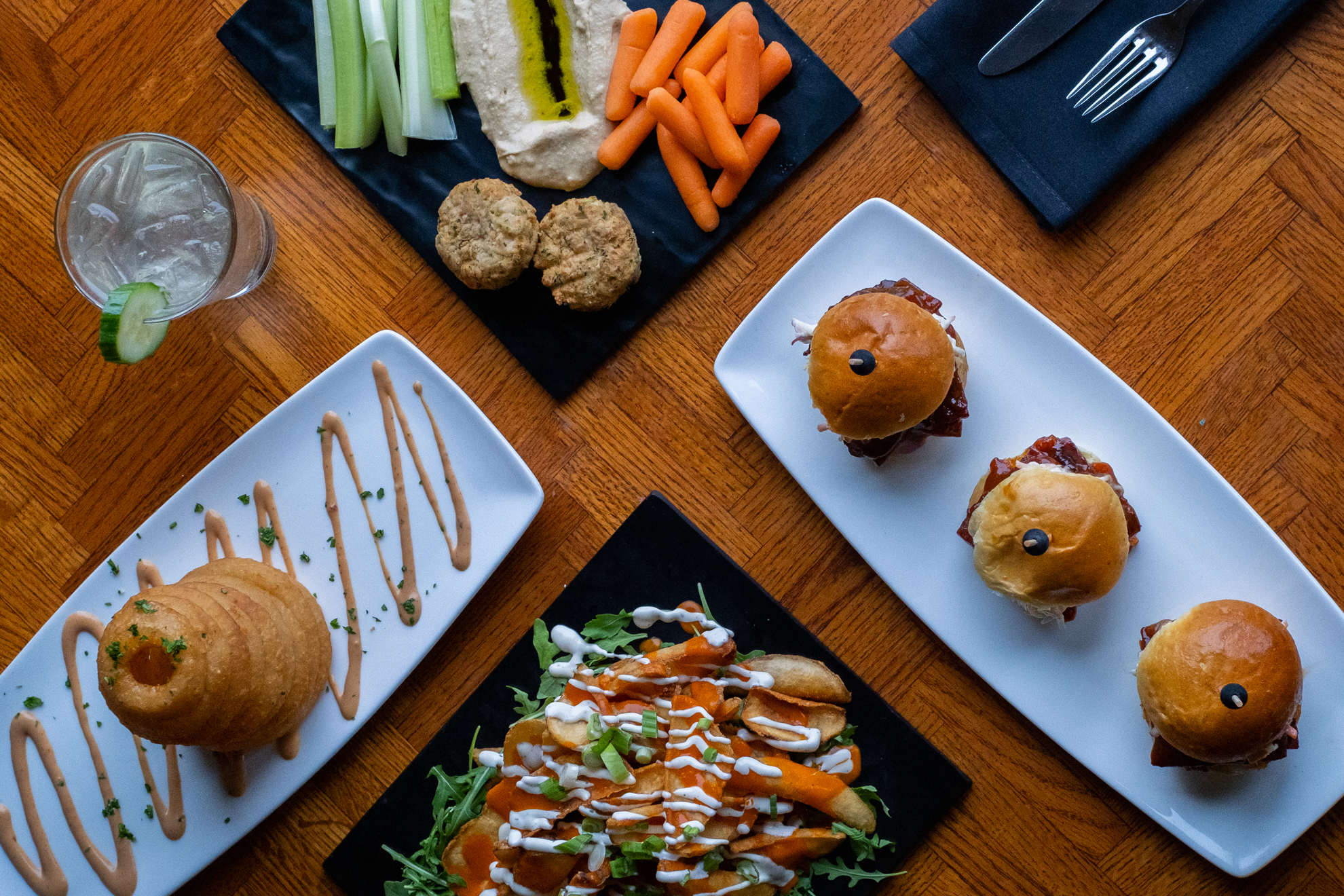 Overhead view of appetizers: slider burgers, onion rings, cookies, vegetables.