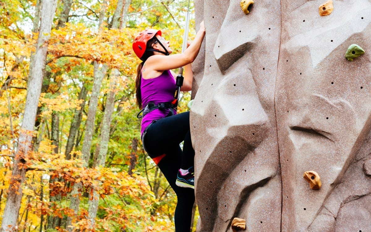 Woman climbing outdoor rock wall.
