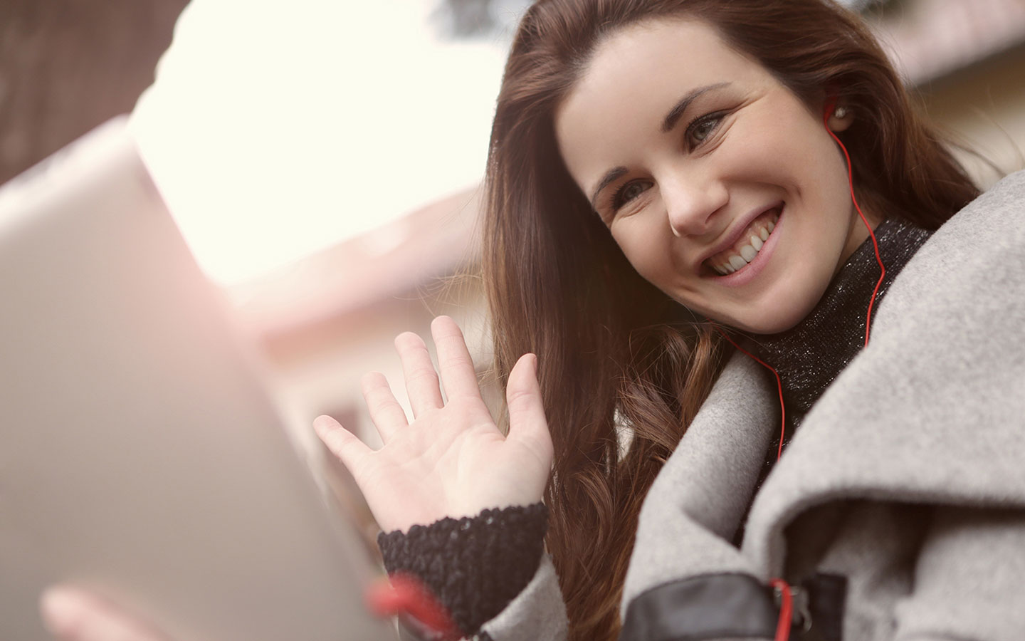 Woman waving to a webcam on her laptop.