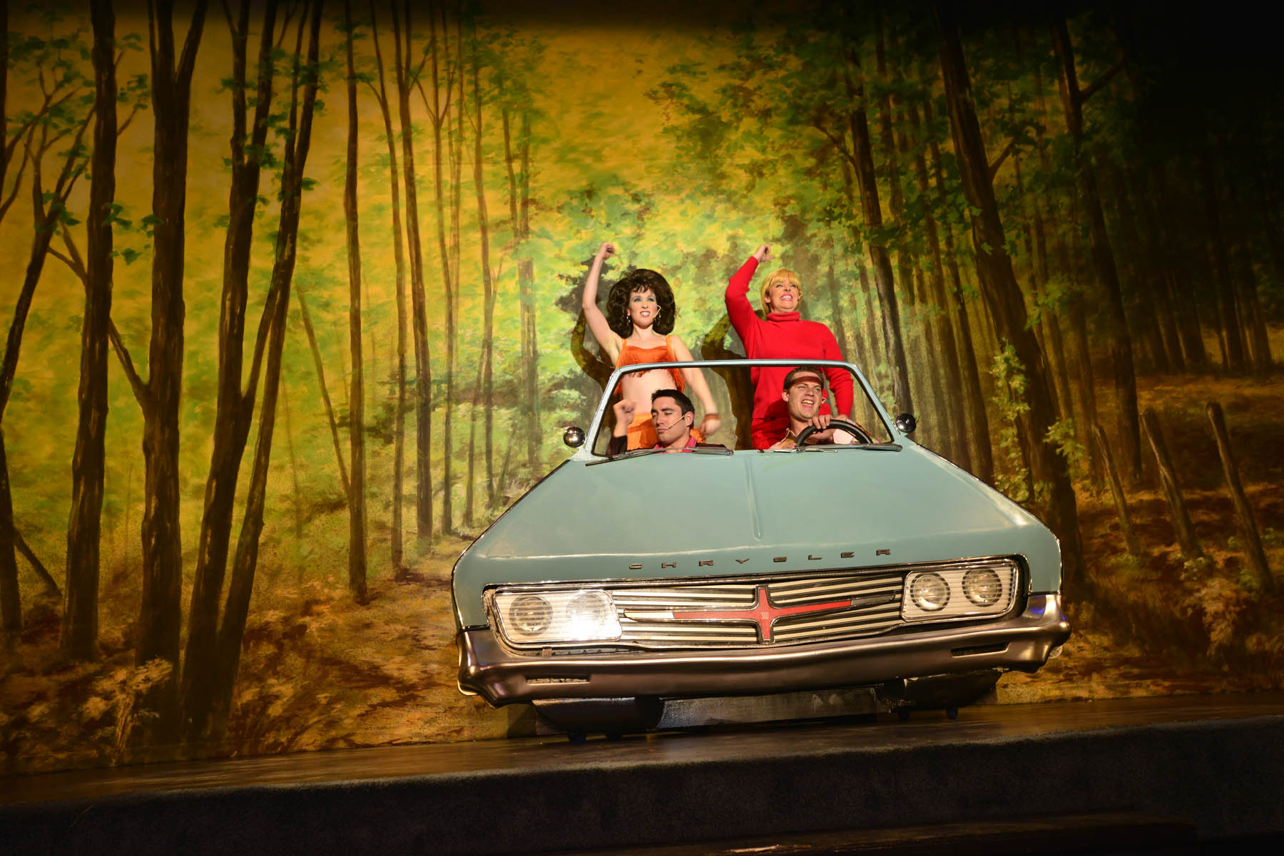 Performers on stage in a fake car.