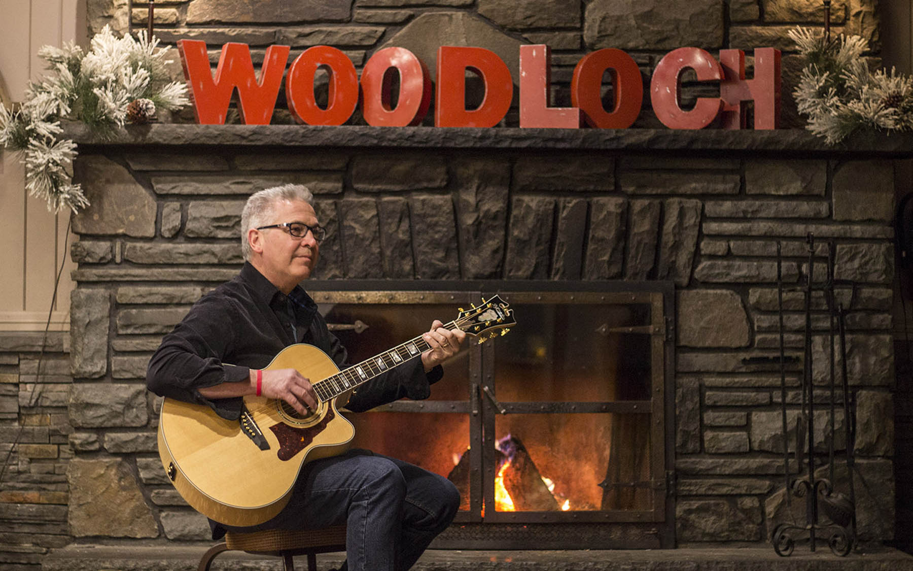 Acoustic guitarist next to a fireplace.
