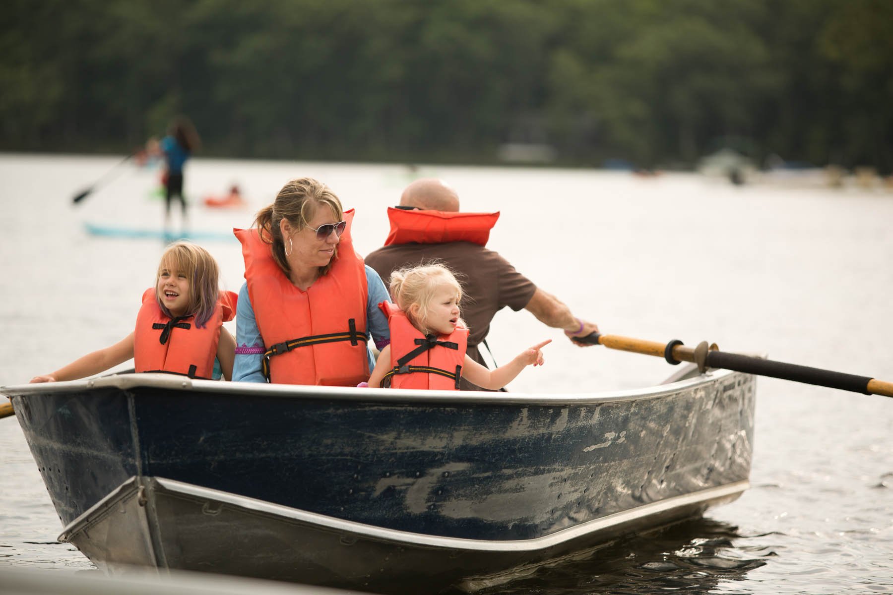 Family in a rowboat wearing lifejackets.