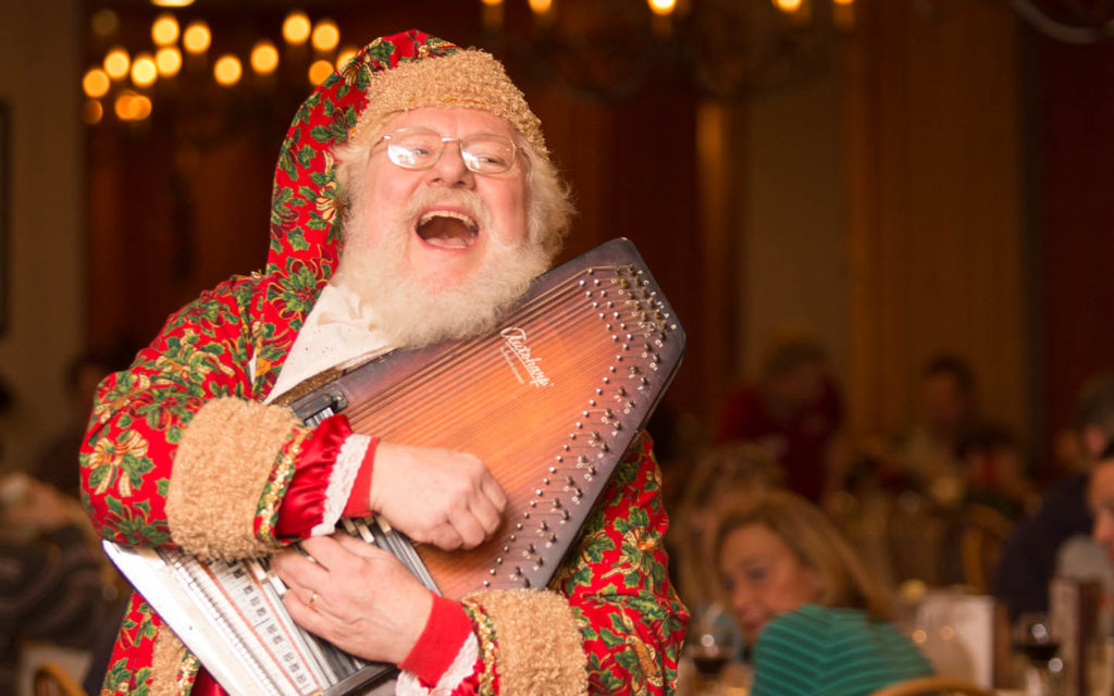 Santa playing an autoharp and singing at dinner.