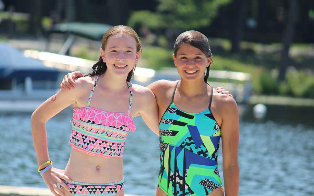 Two young women in swimsuits posing on the dock.