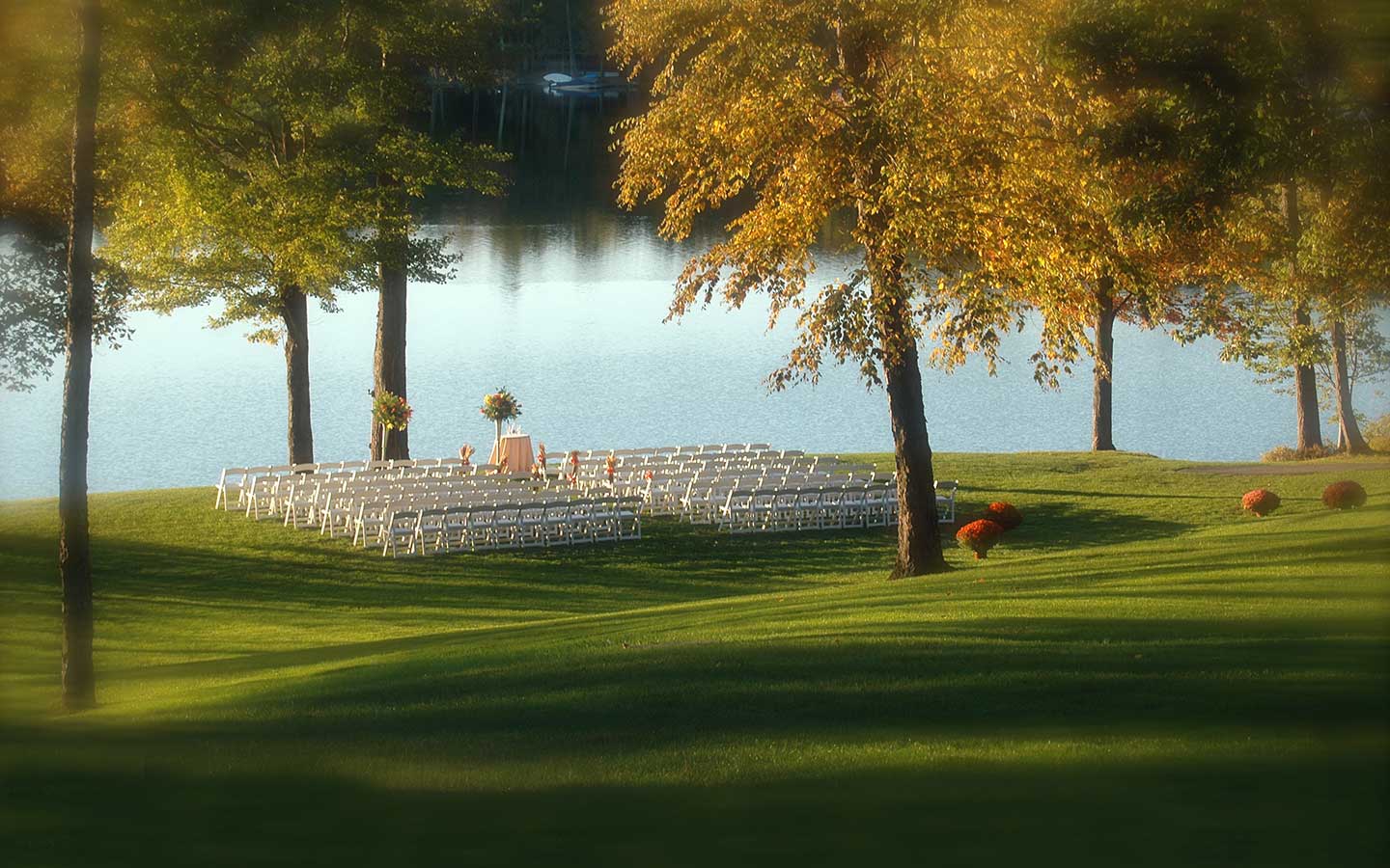 Distant photo of lakeside wedding ceremony setup.