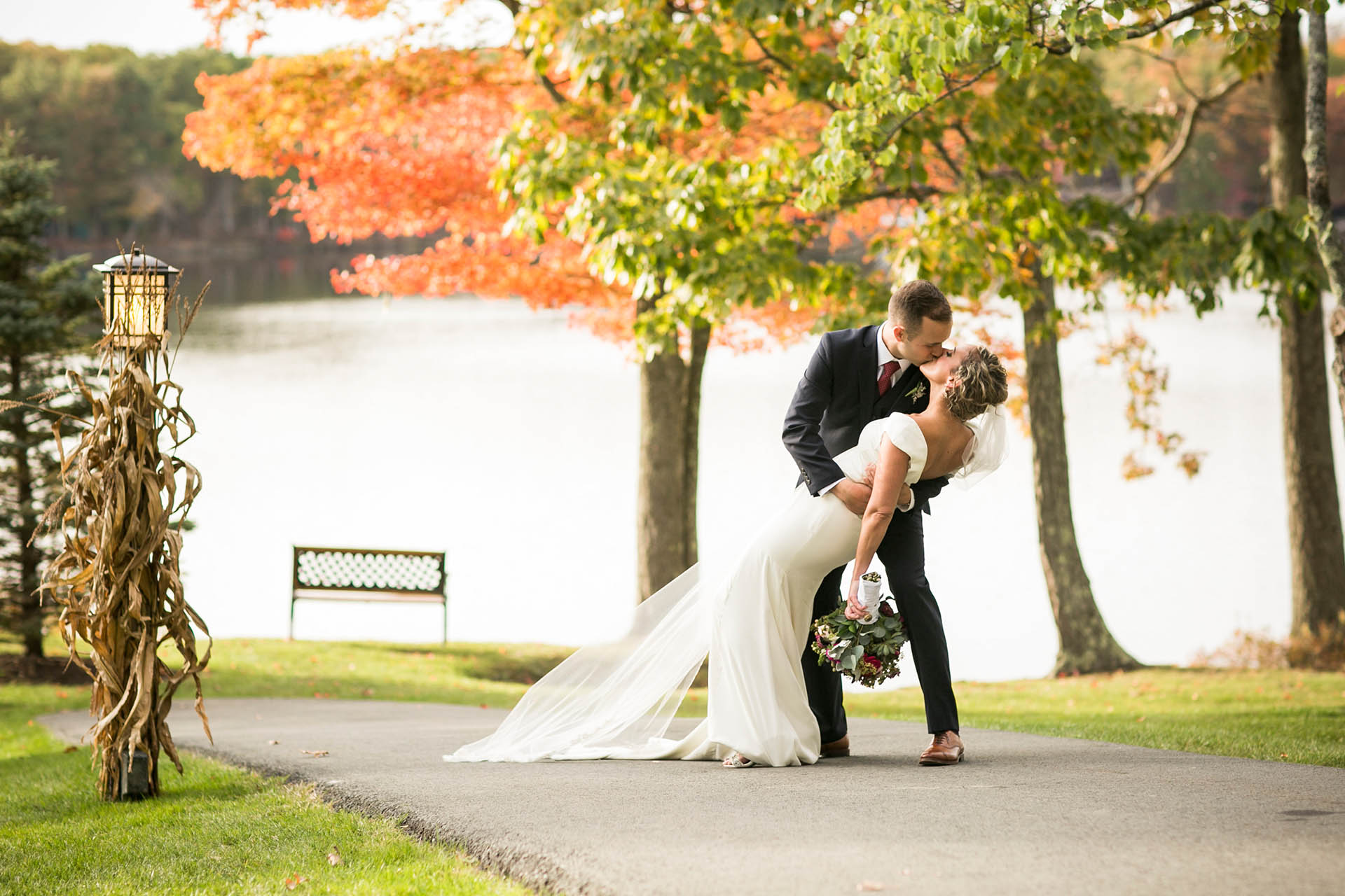 Groom dipping bride on autumn trail.