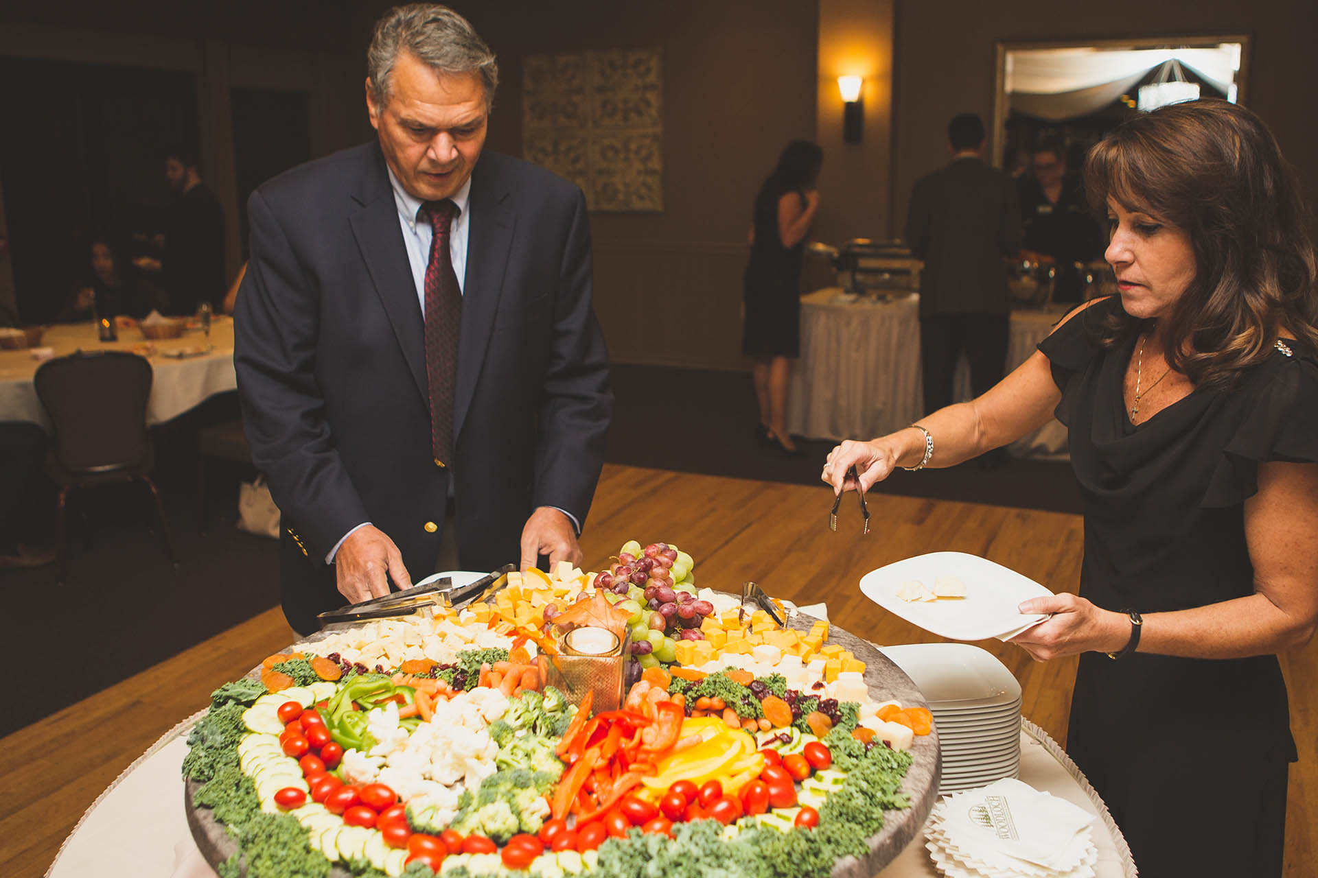 Wedding reception guests picking vegetables from large veggie tray.