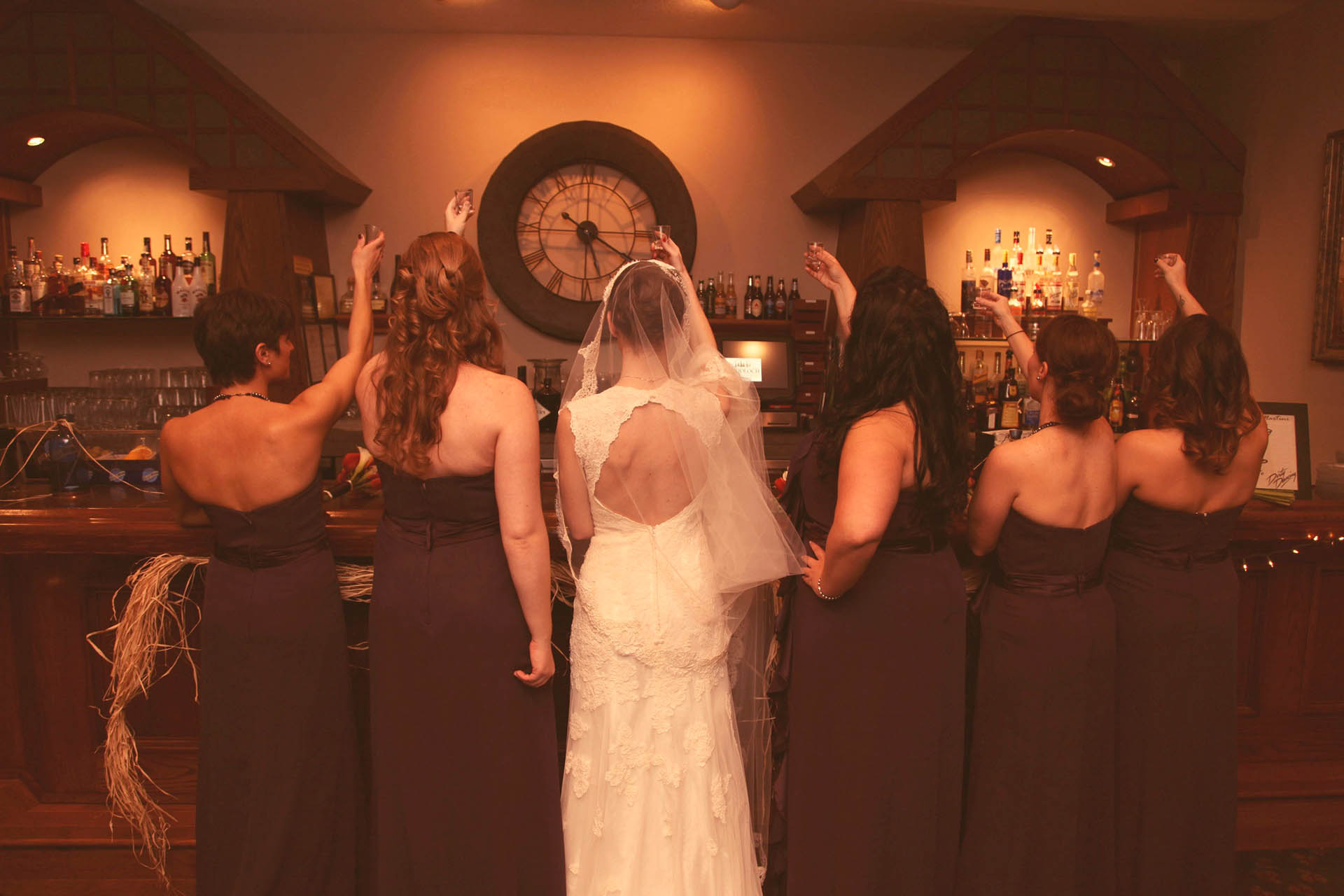 Bride and Bridesmaids toasting a drink at the bar.