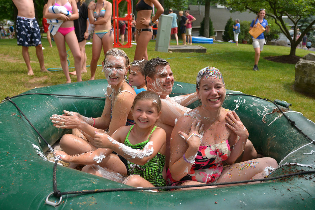 Group of young women in a kiddie pool with whipped cream and chocolate.