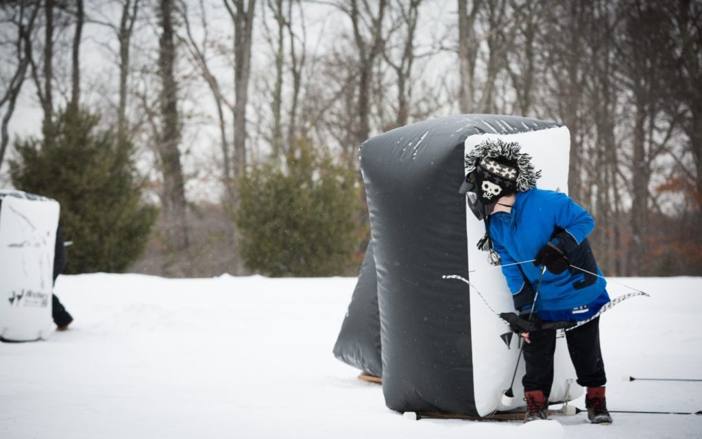 Person with faux bow and arrow behind an inflatable barrier