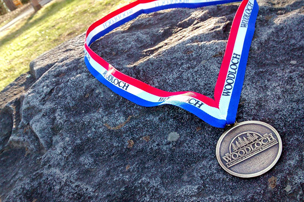 Woodloch OLympics medal laying on a rock.