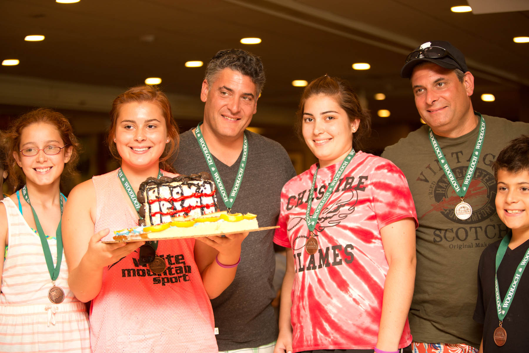 Young women and adults holding cake.