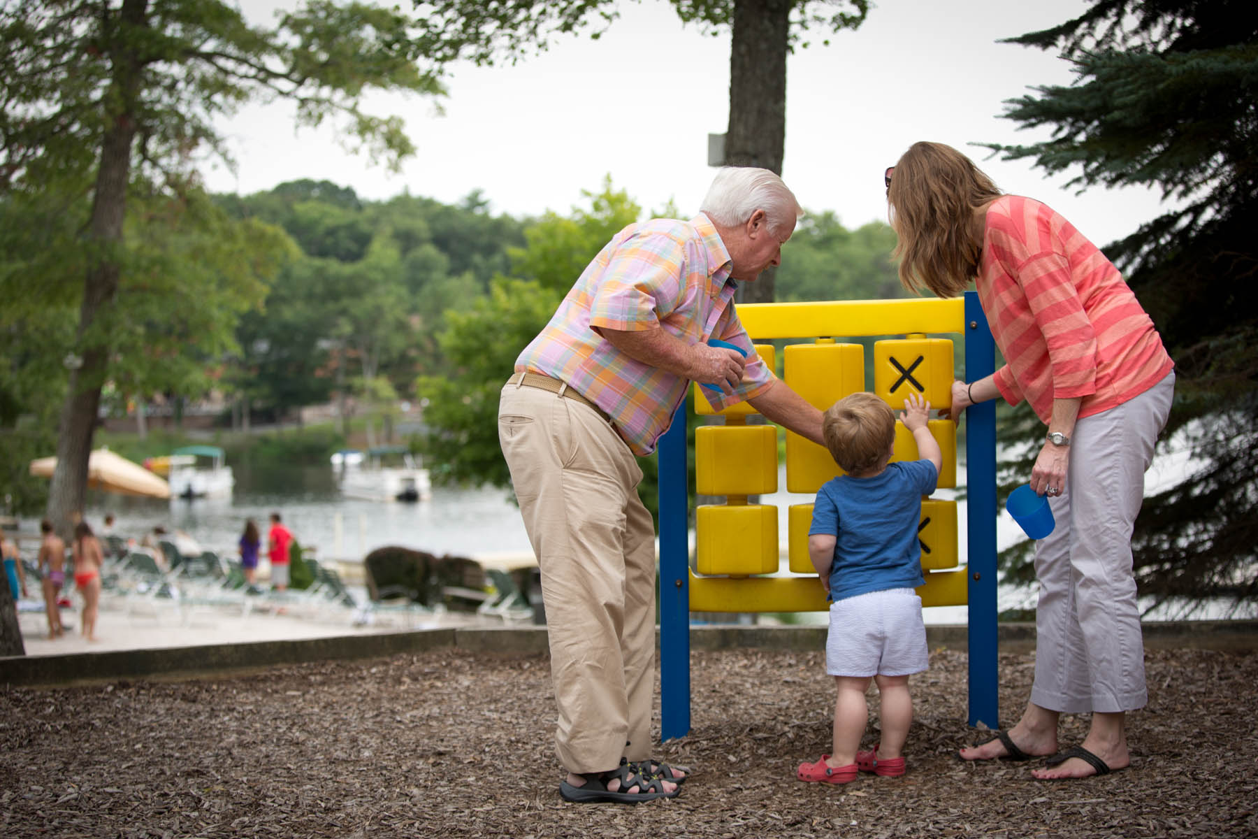 Grandparents and toddler playing with tic-tac-toe board.