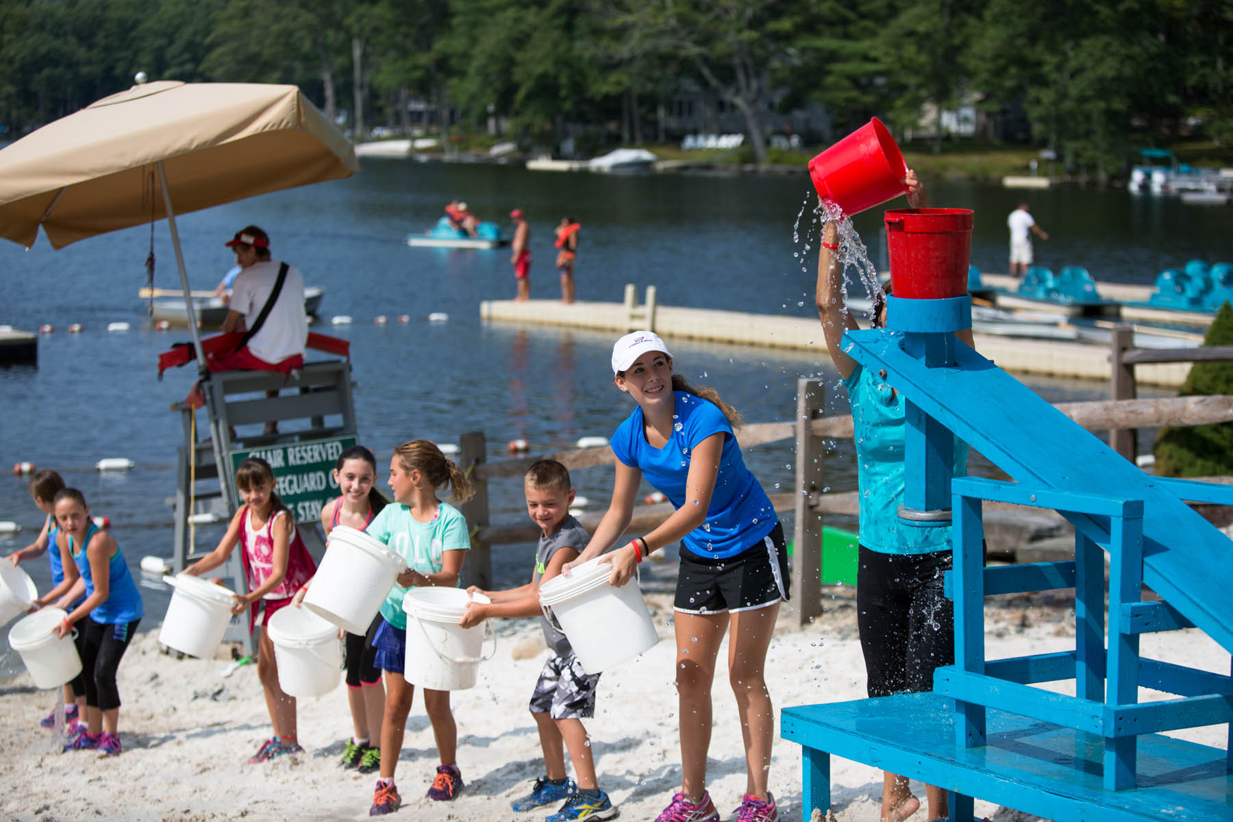 Kids and young woman doing a water bucket race.