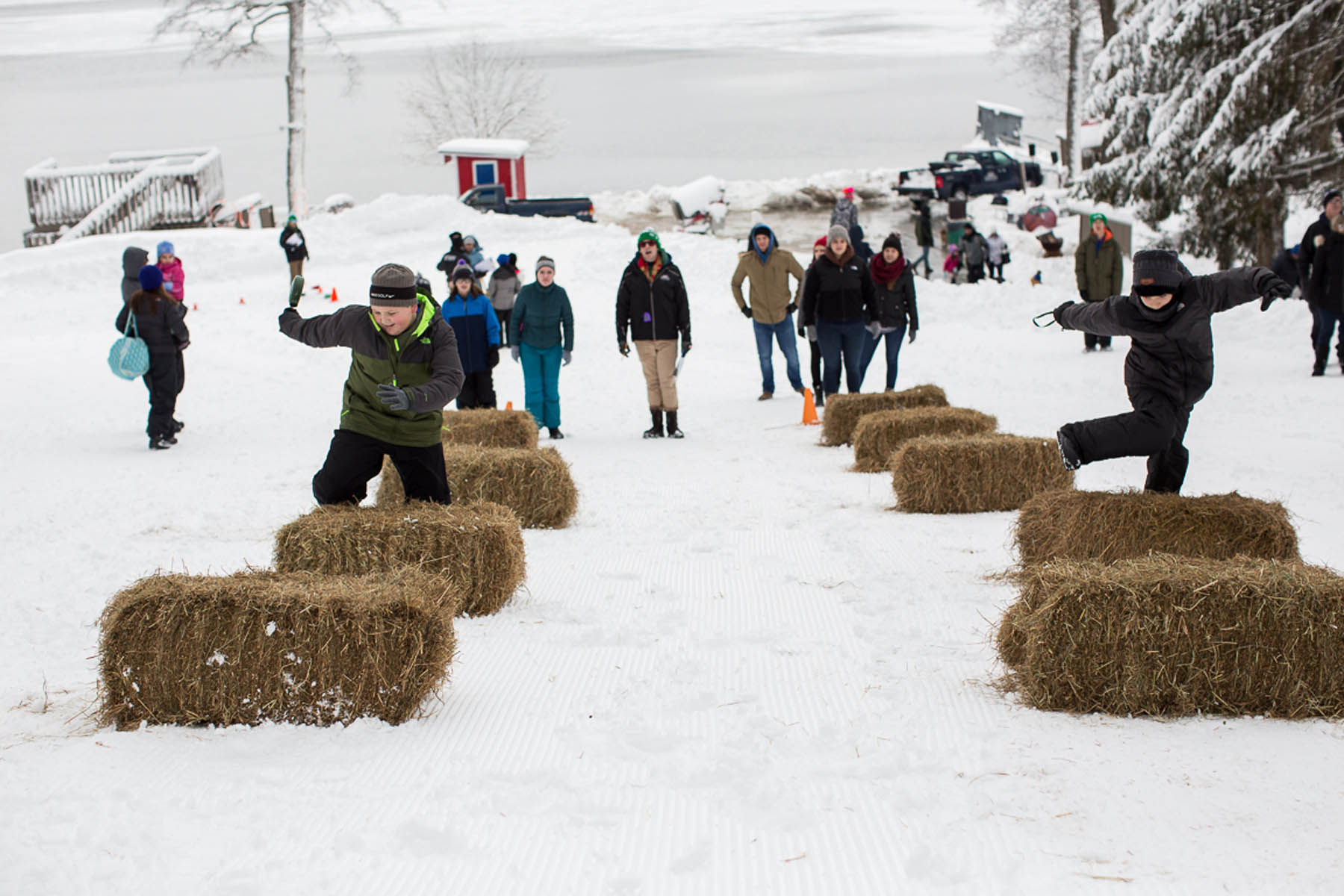 Young boys jumping hay bales in winter.