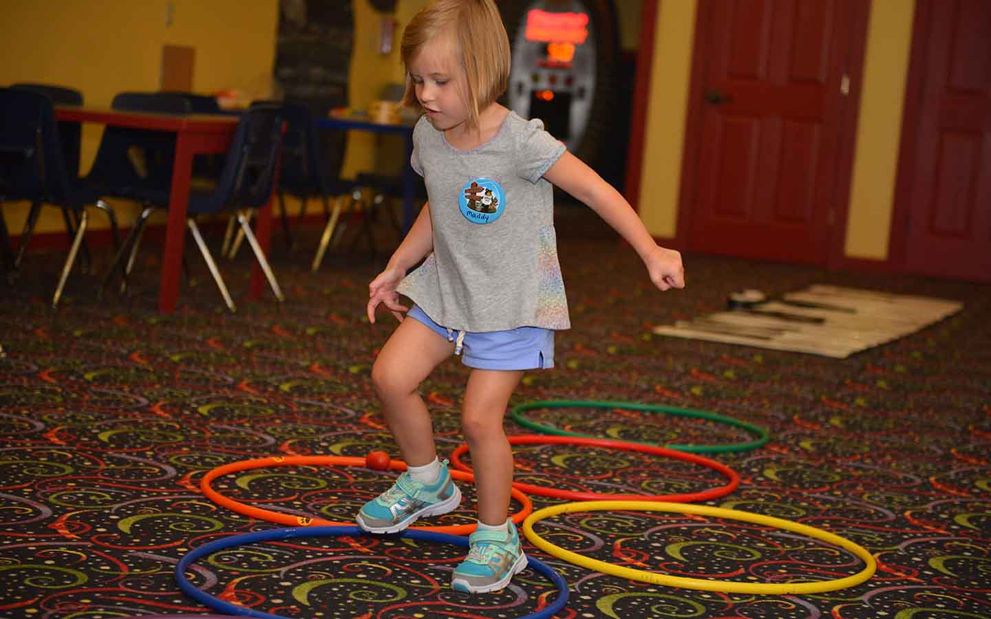Young girl running through hula hoops on floor.