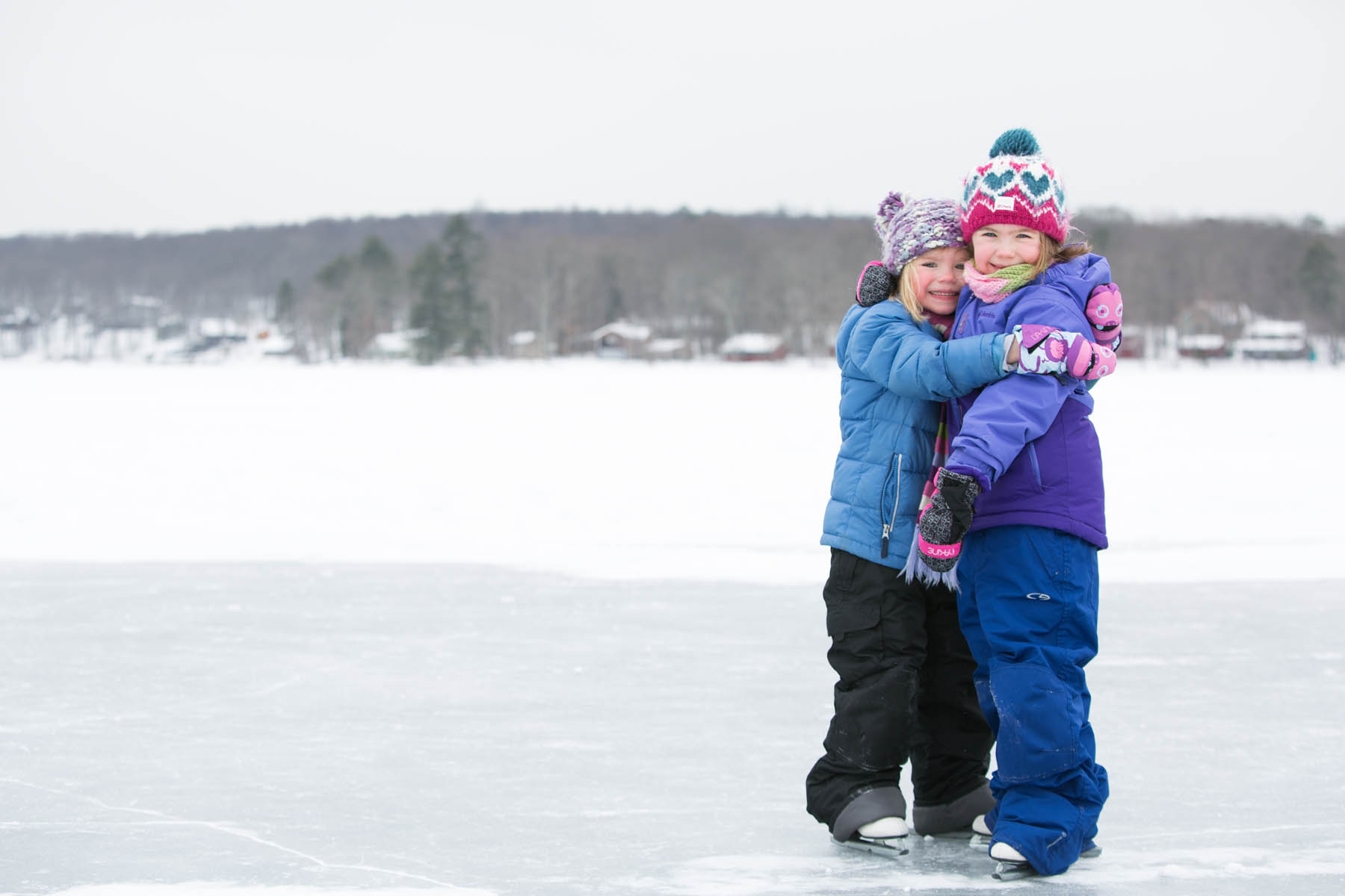 Two young girls hugging outdoors in winter.