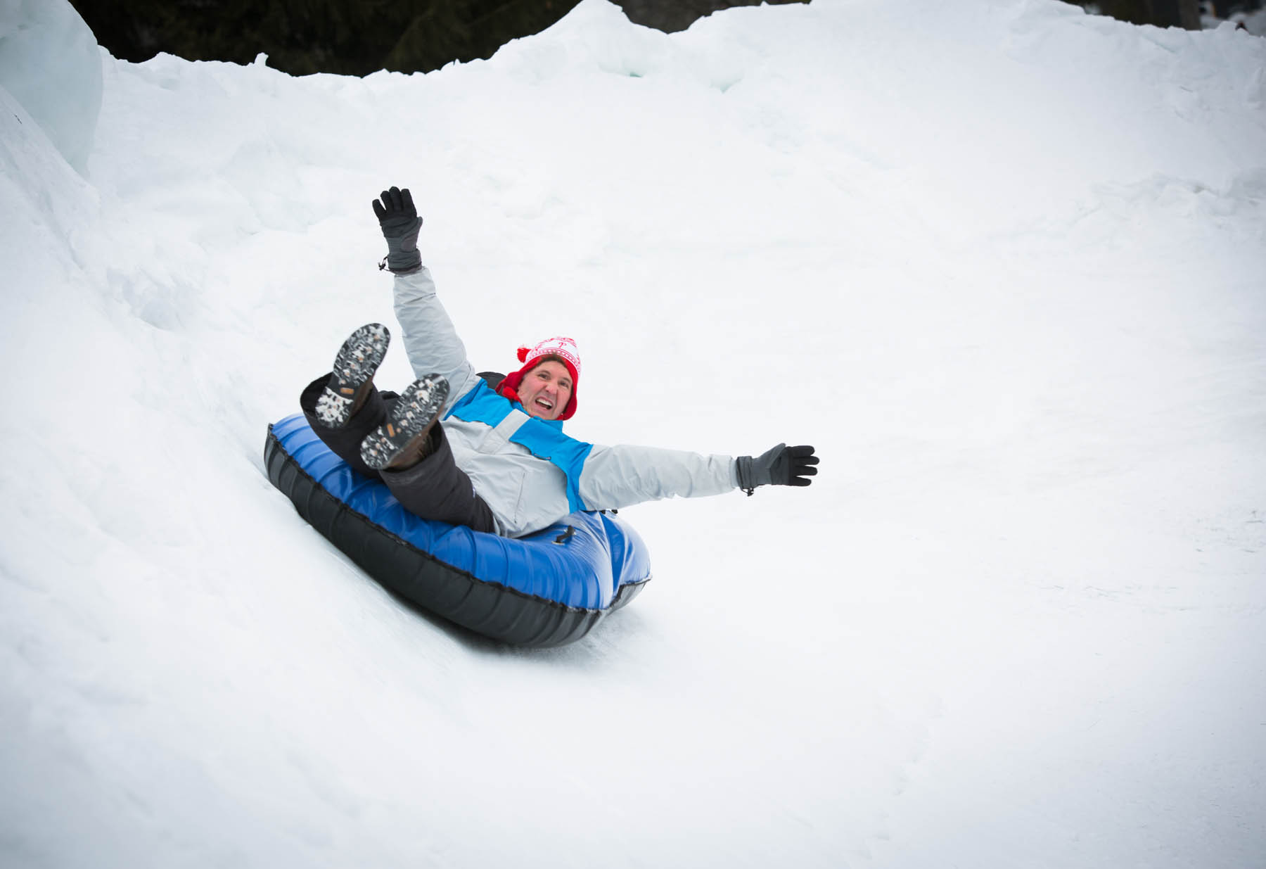 Man sitting in large snow tube.