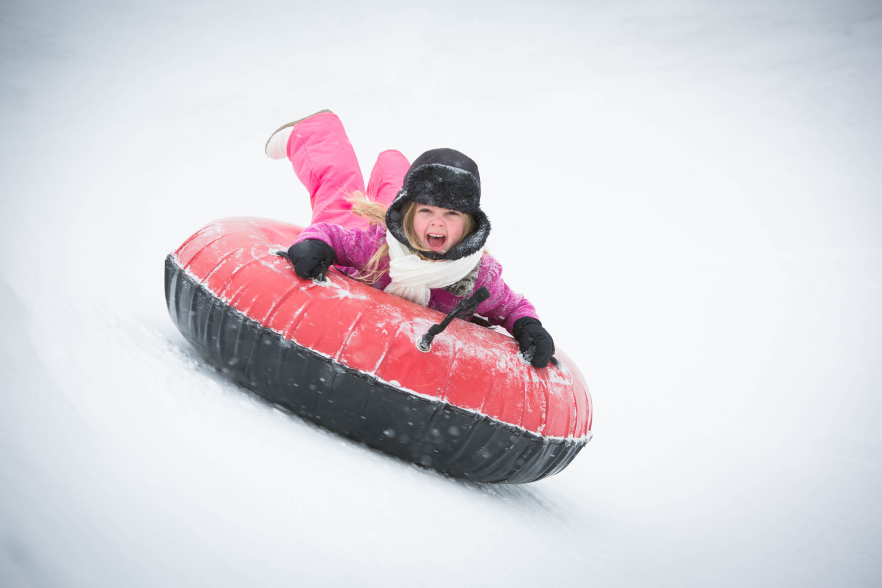 Young girl going downhill on an inner tube.