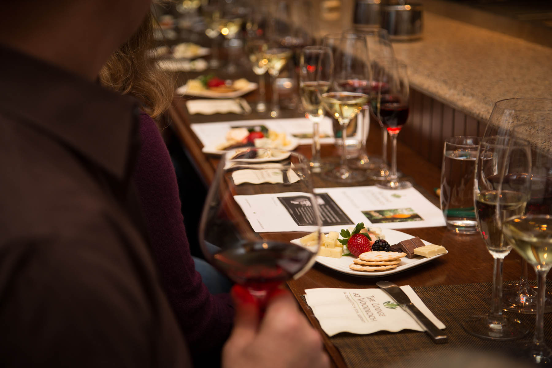 Close up of person's glass of liquor and charcutier board.