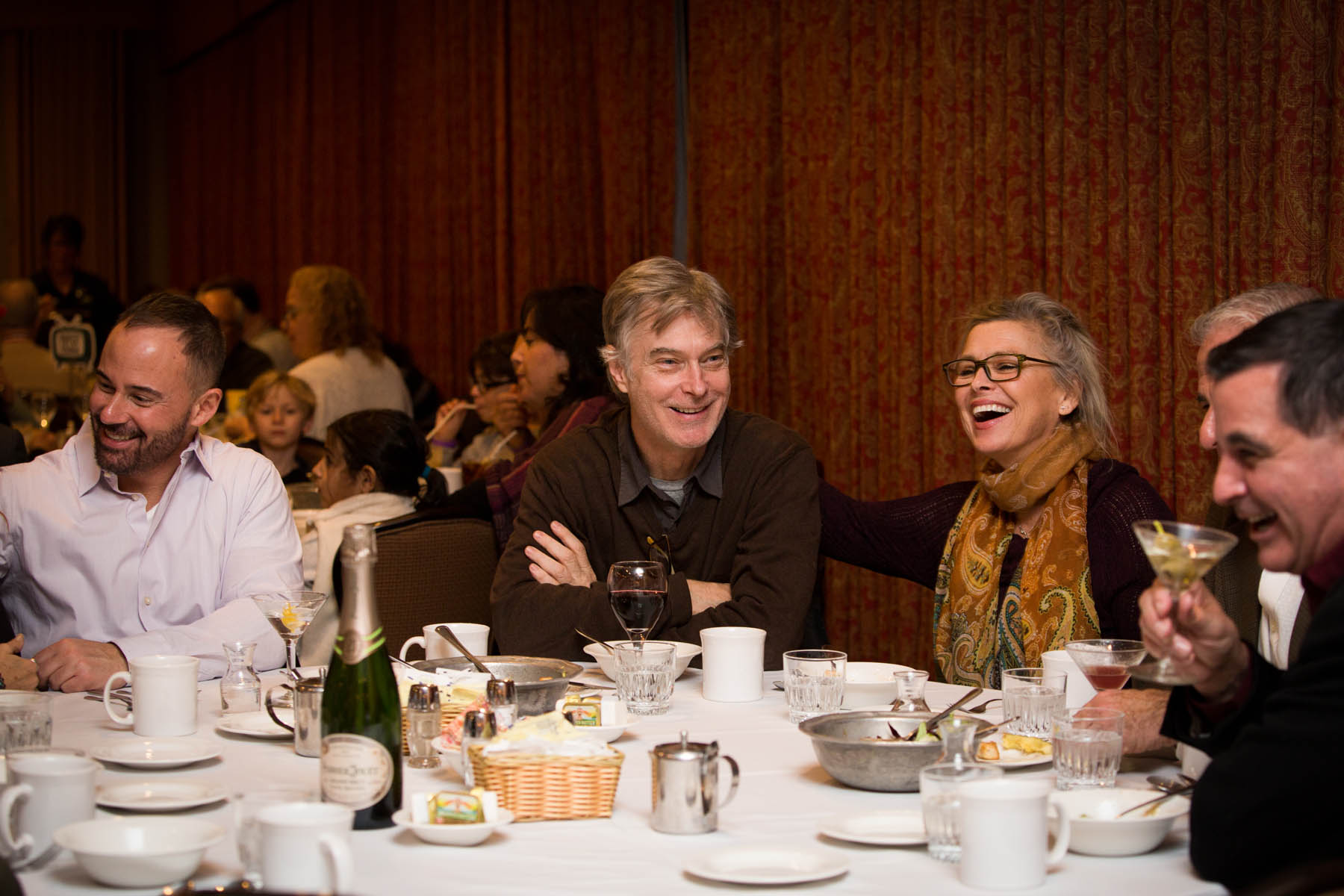 Group of friends at dining table laughing and smiling.