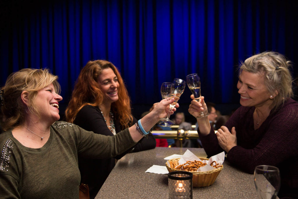 Three women toasting wine at dinner.