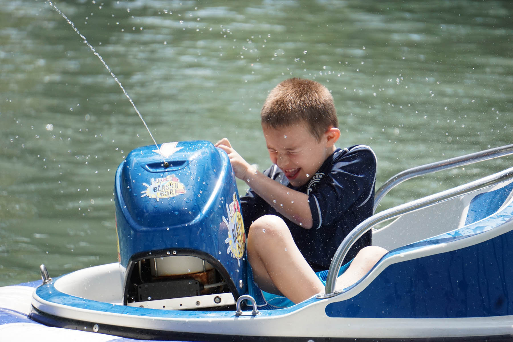 Young boy firing water from bumper boat blaster.
