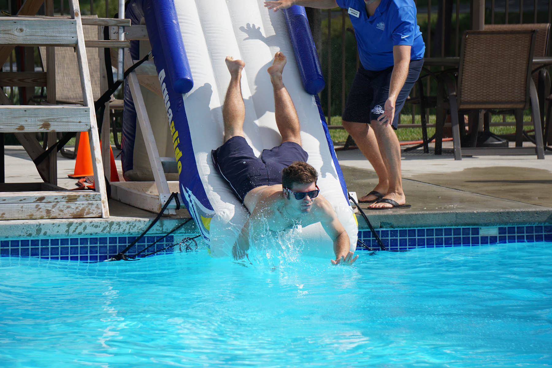 Young man sliding into the pool face first.