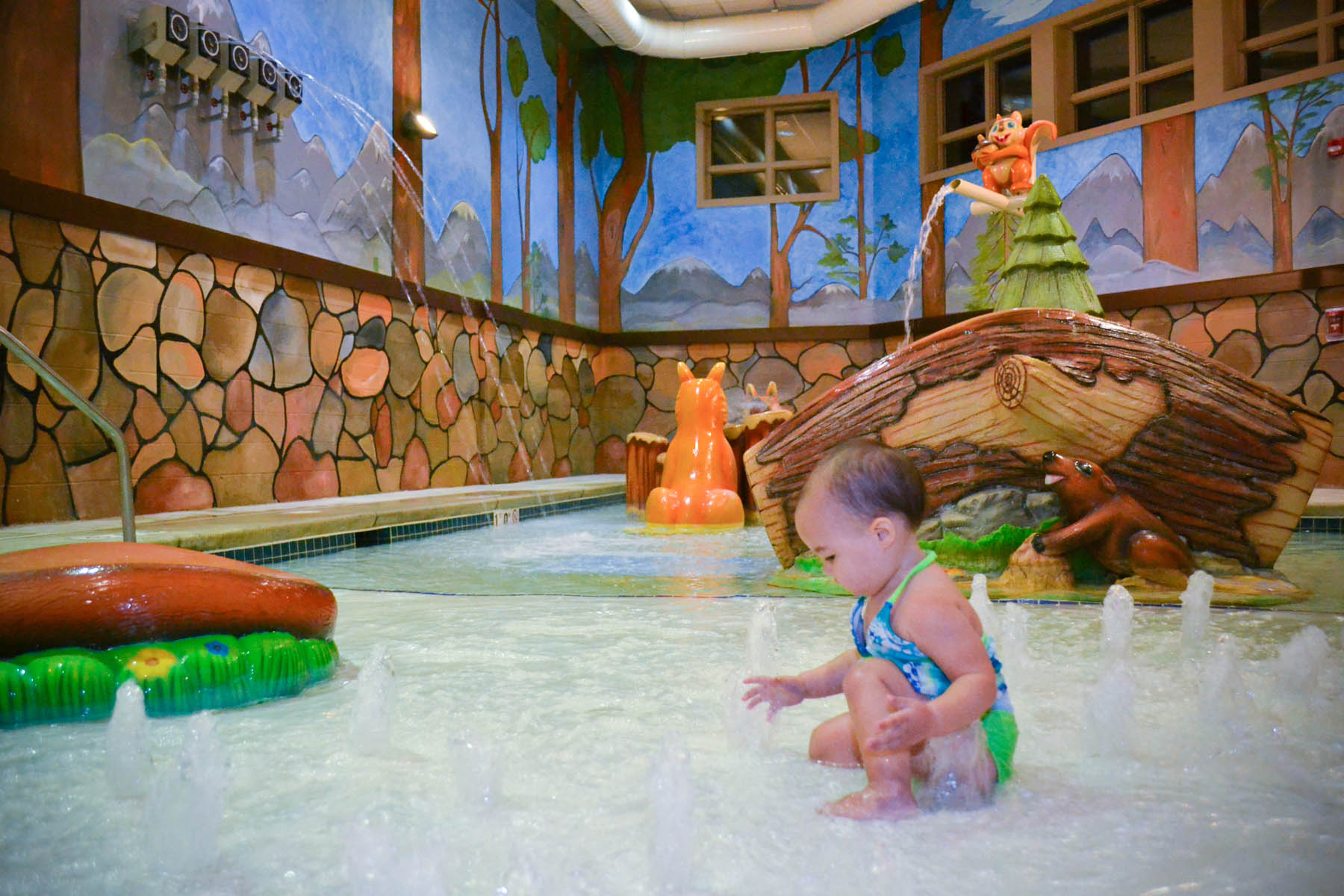 Toddler playing in splashpad fountains.