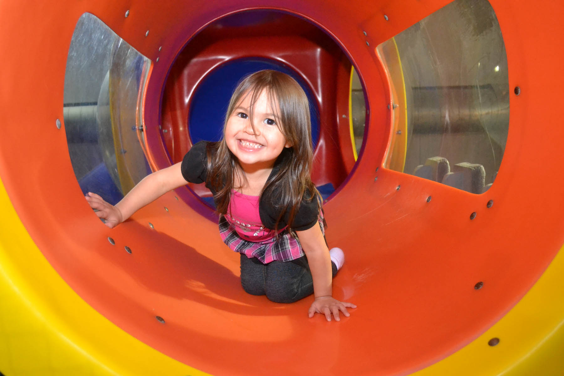 Young girl in a playground tunnel.