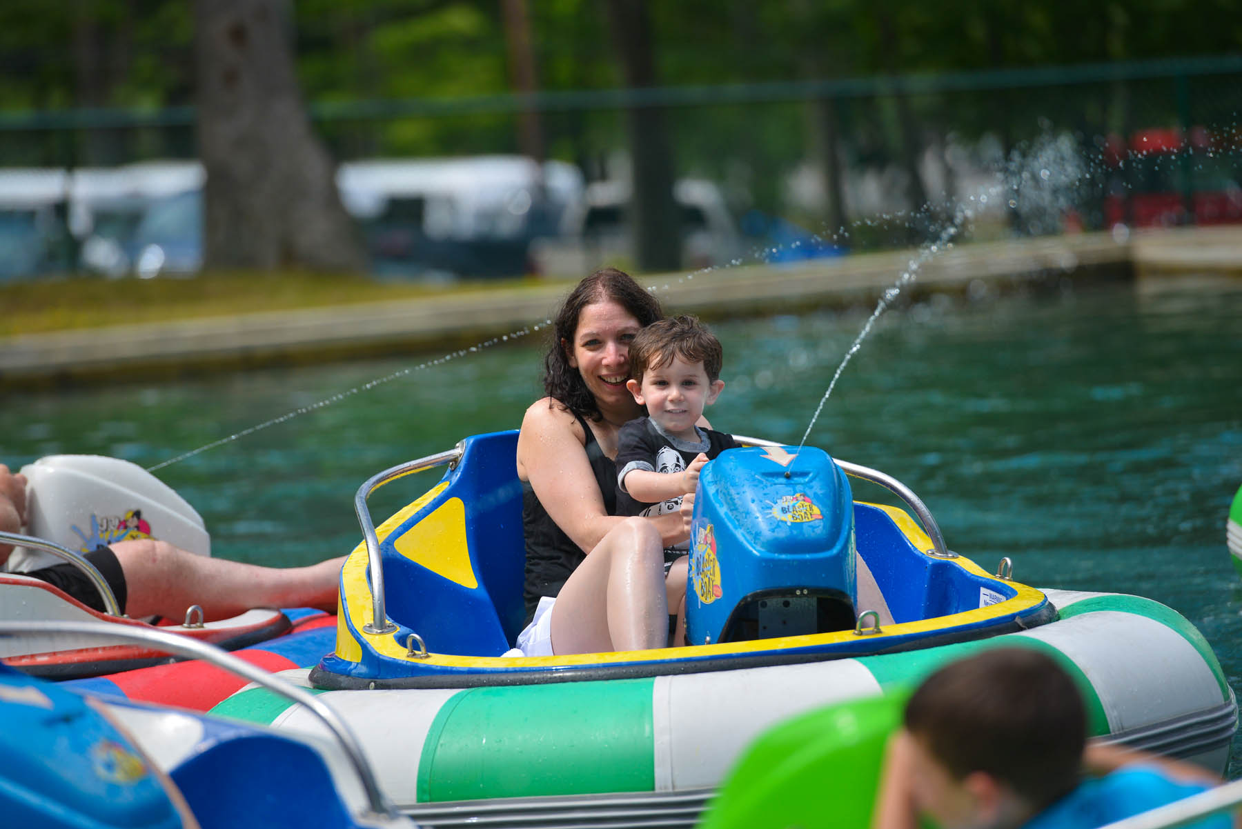 Mother and son in bumper boat spraying water.