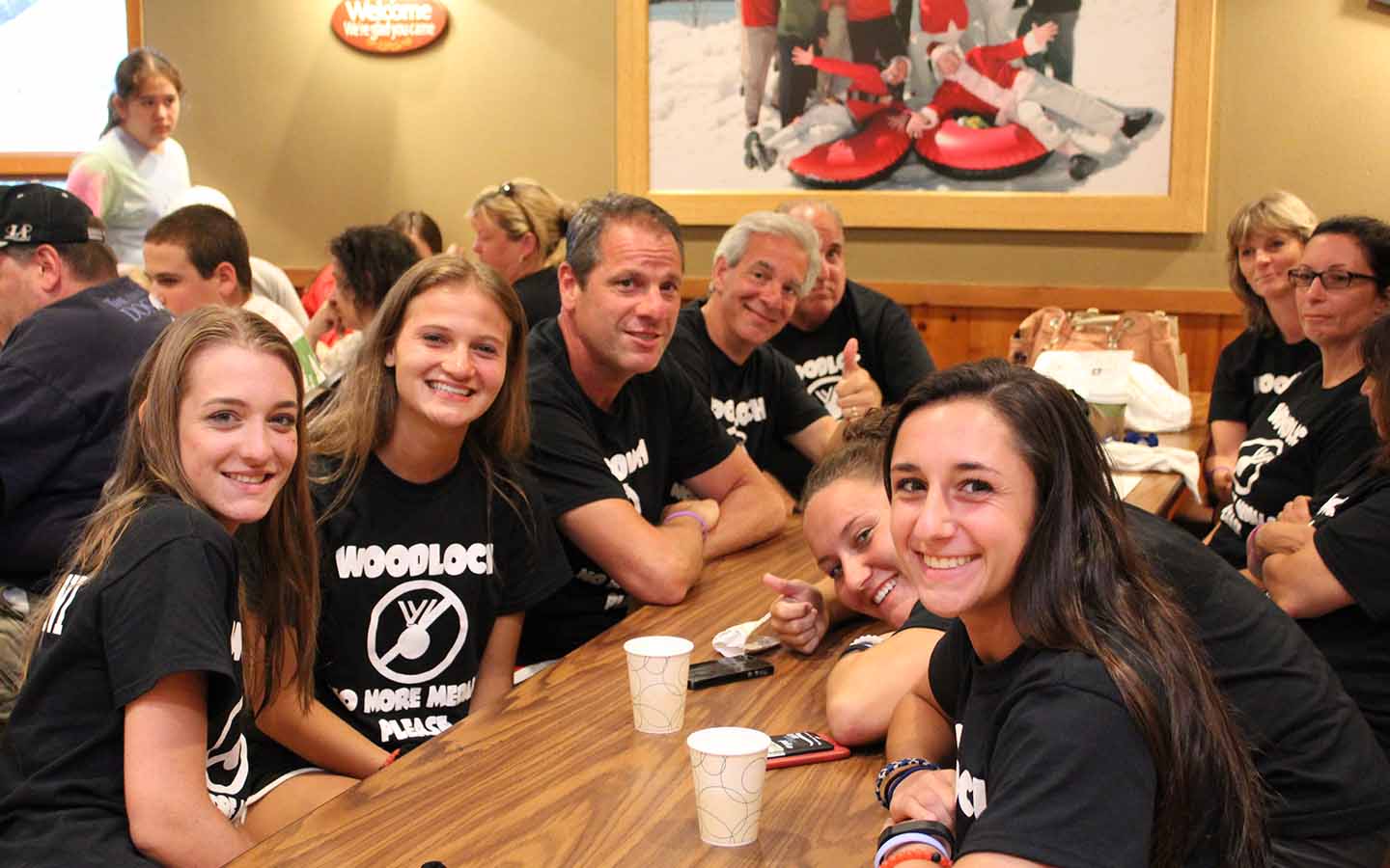 Group of parents and young women at table in matching black t-shirts.