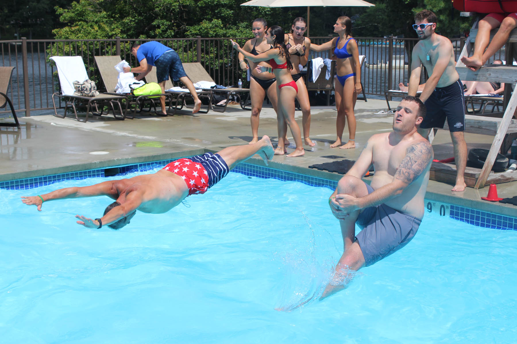 Two men diving into the outdoor pool.