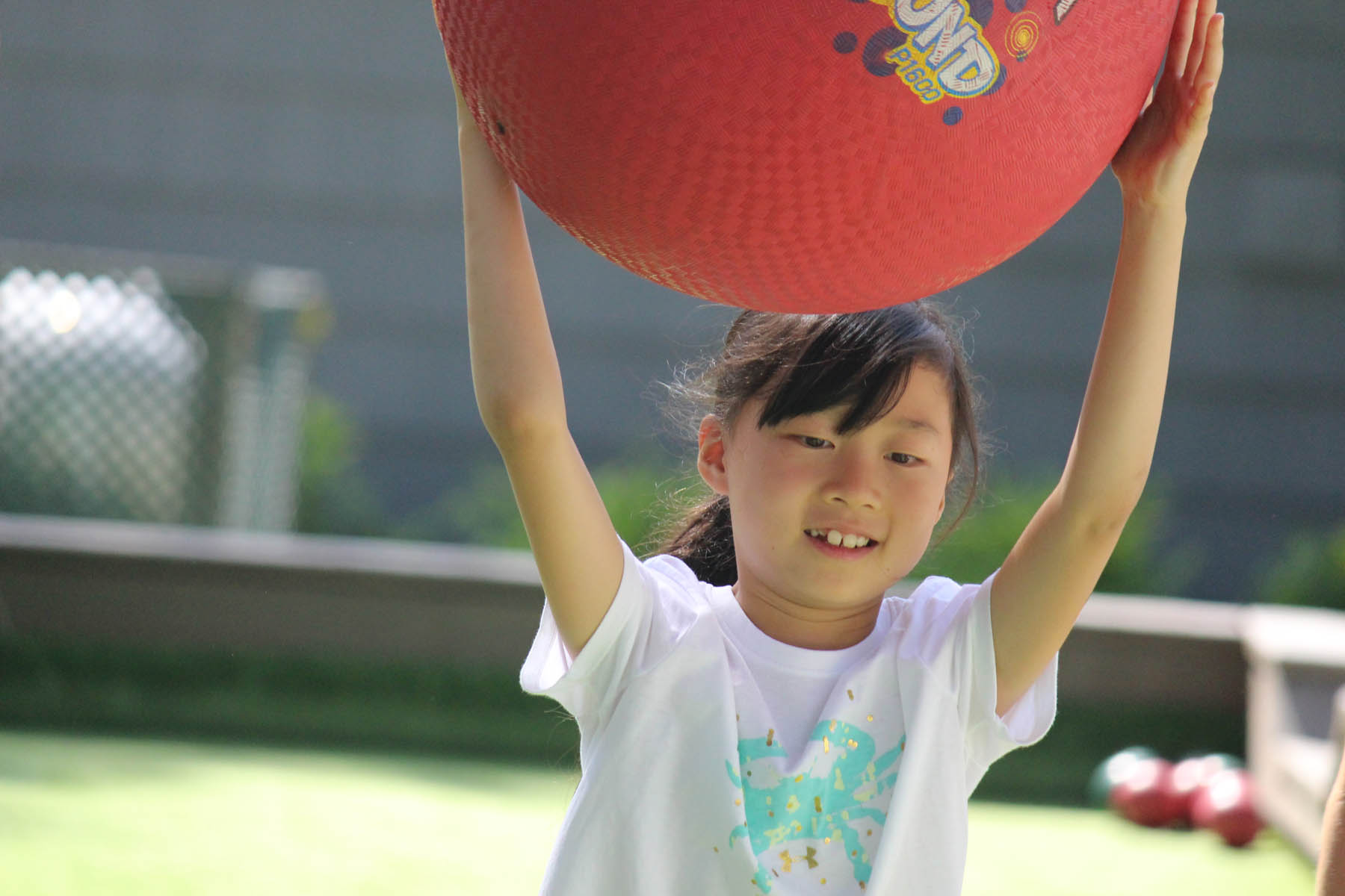 Young girl with a large bouncy ball on her head.