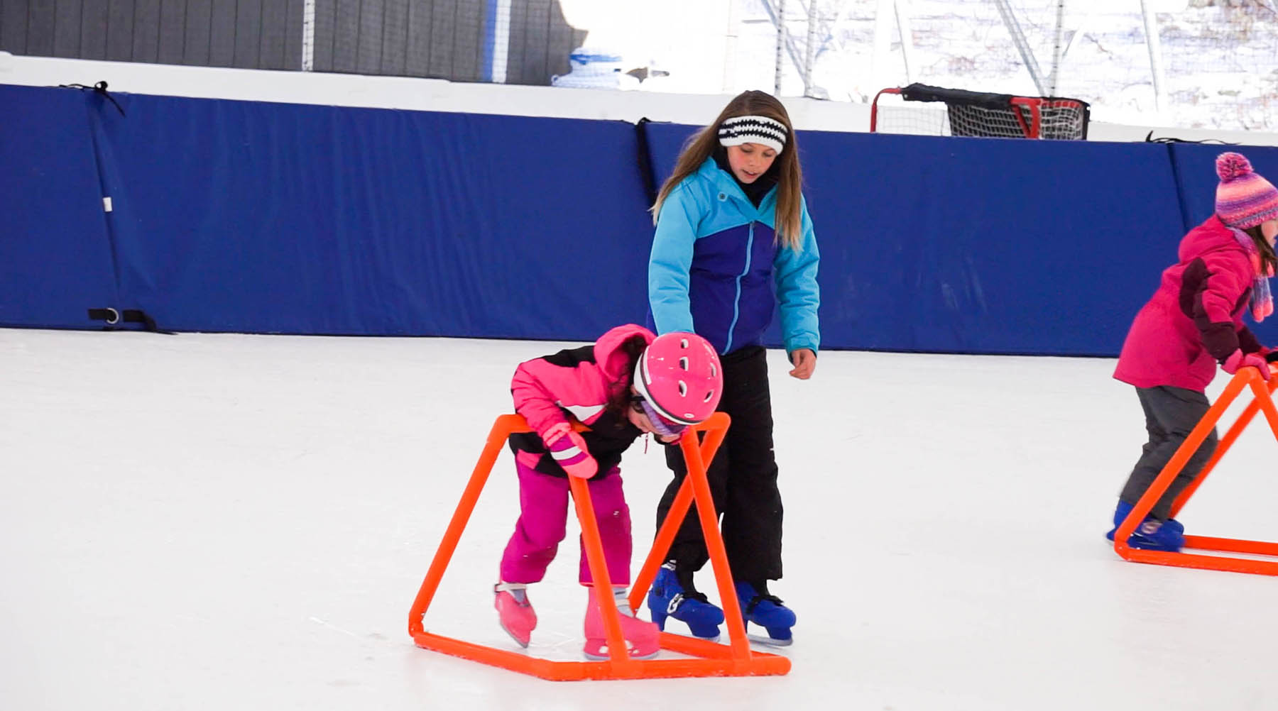 Young girl learning to skate with teacher.