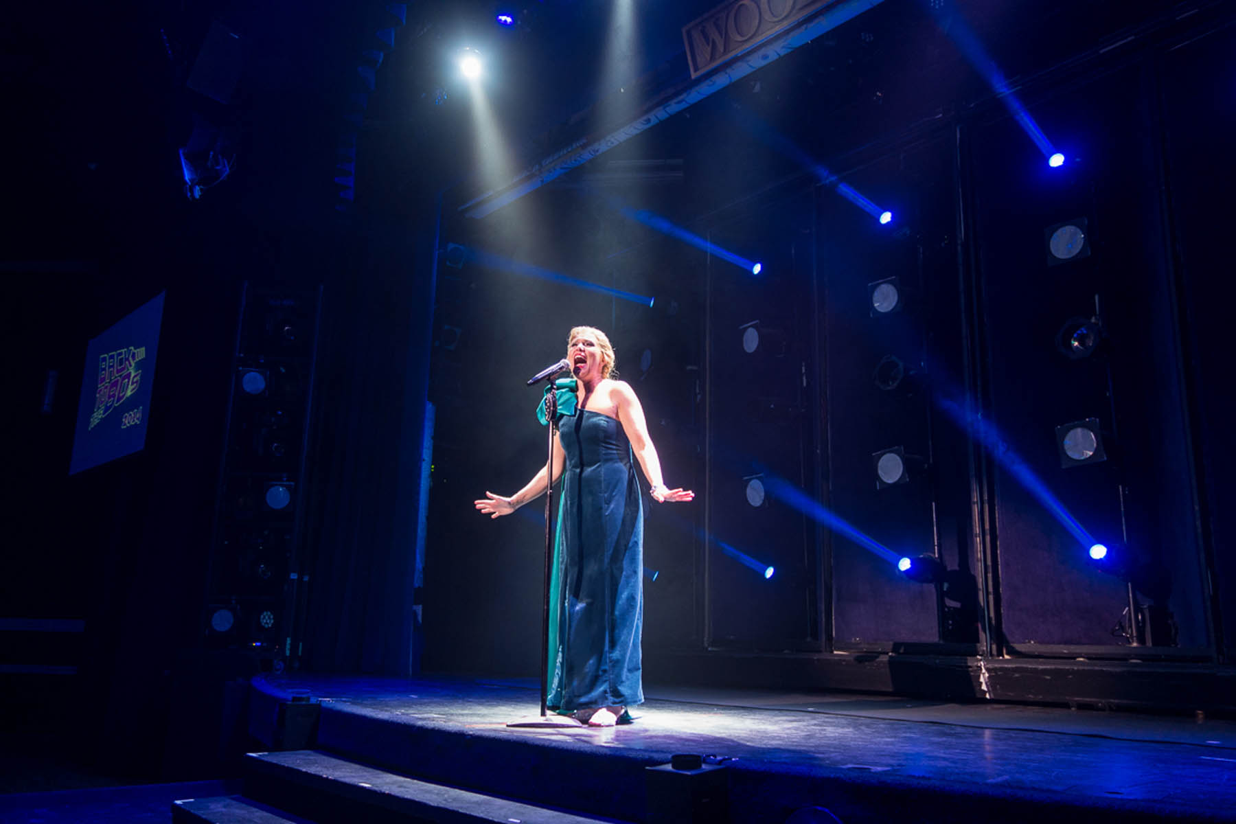 Woman in blue dress singing.