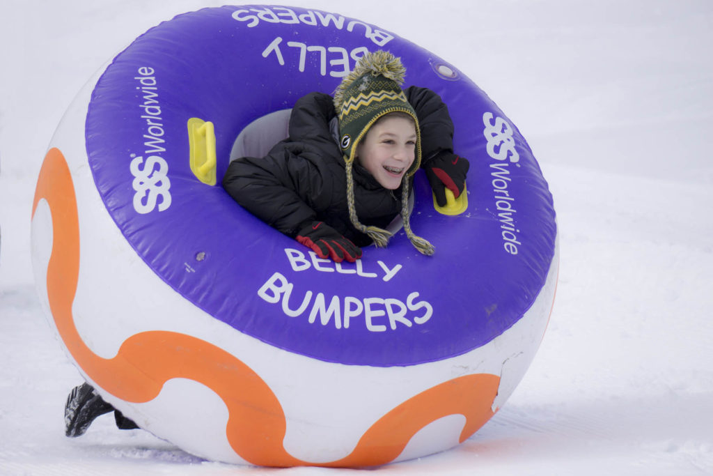 Young person in a belly bumper inner tube in winter.