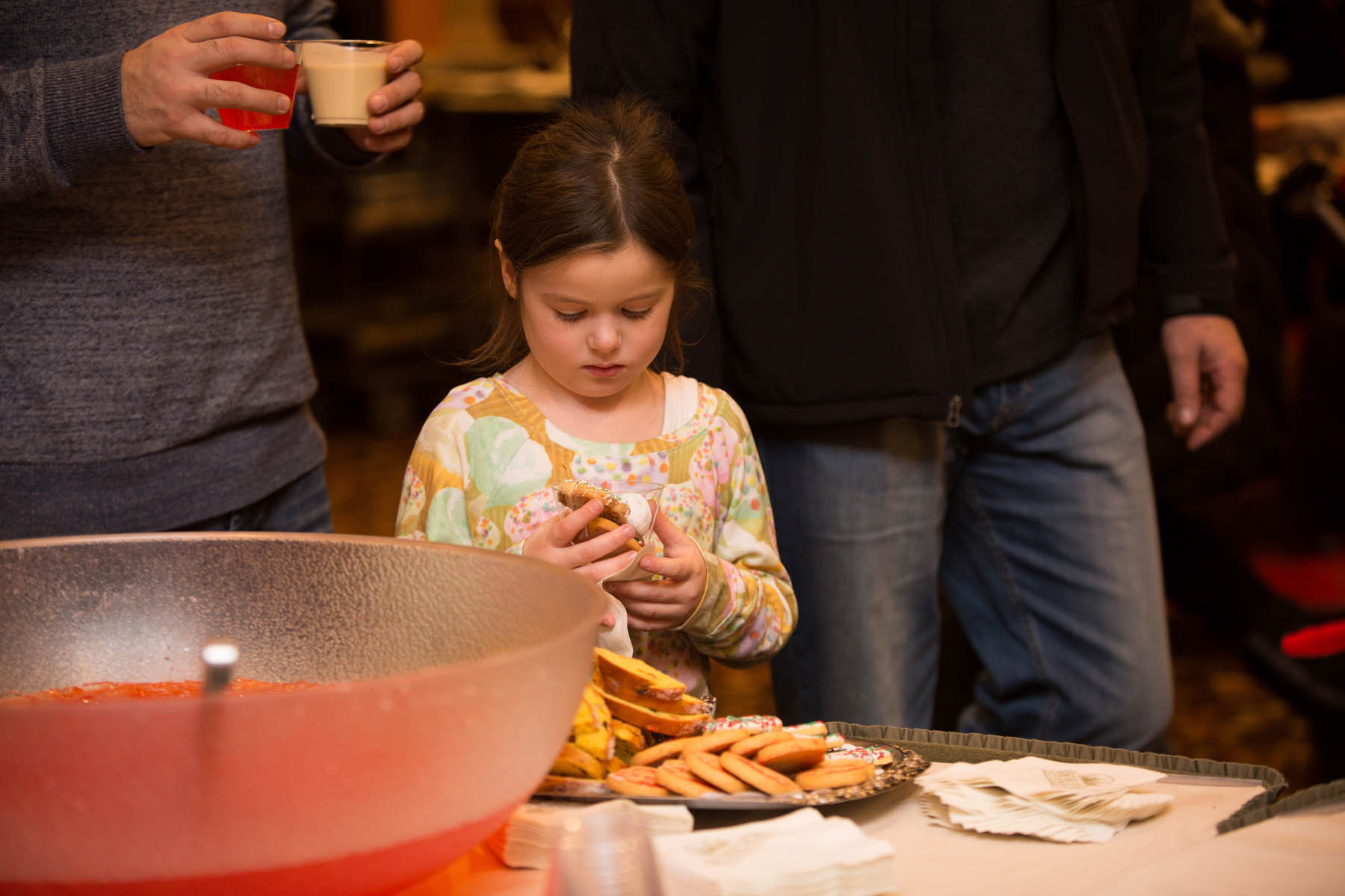 Young girl holding cup of Christmas cookies.