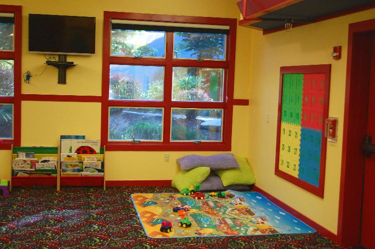 Kids Club room interior with television, books and floor pillows.