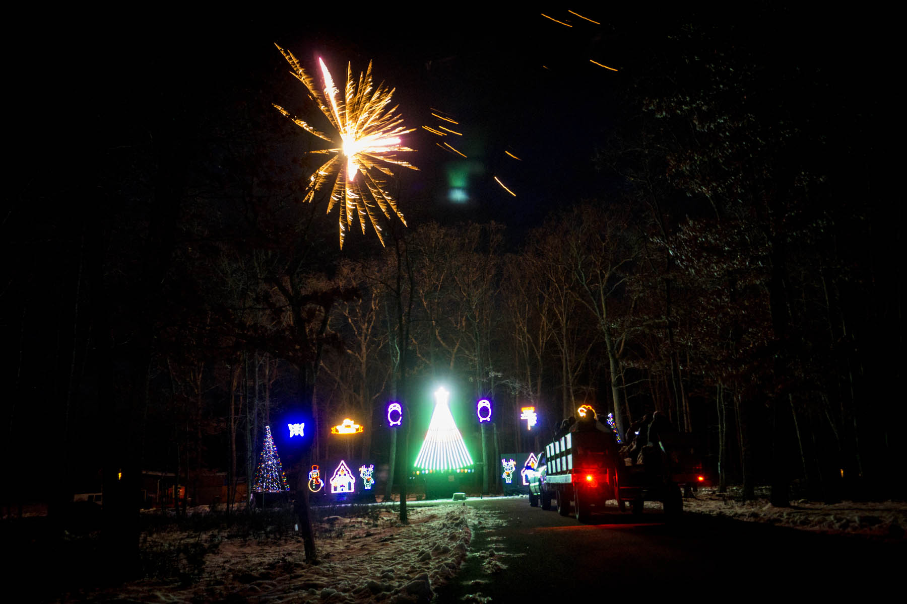 Fireworks over outdoor Holiday lights.