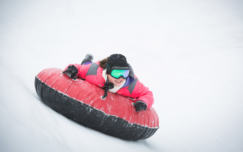 Young person sliding downhlll in an inner tube.