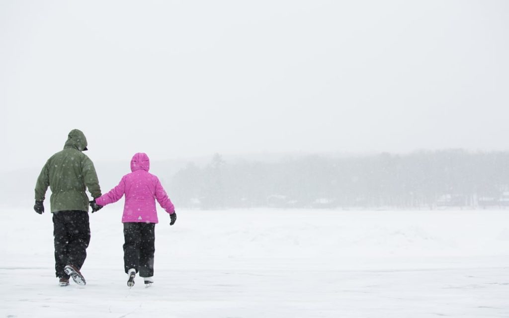 Two people walking on the lake in snow.