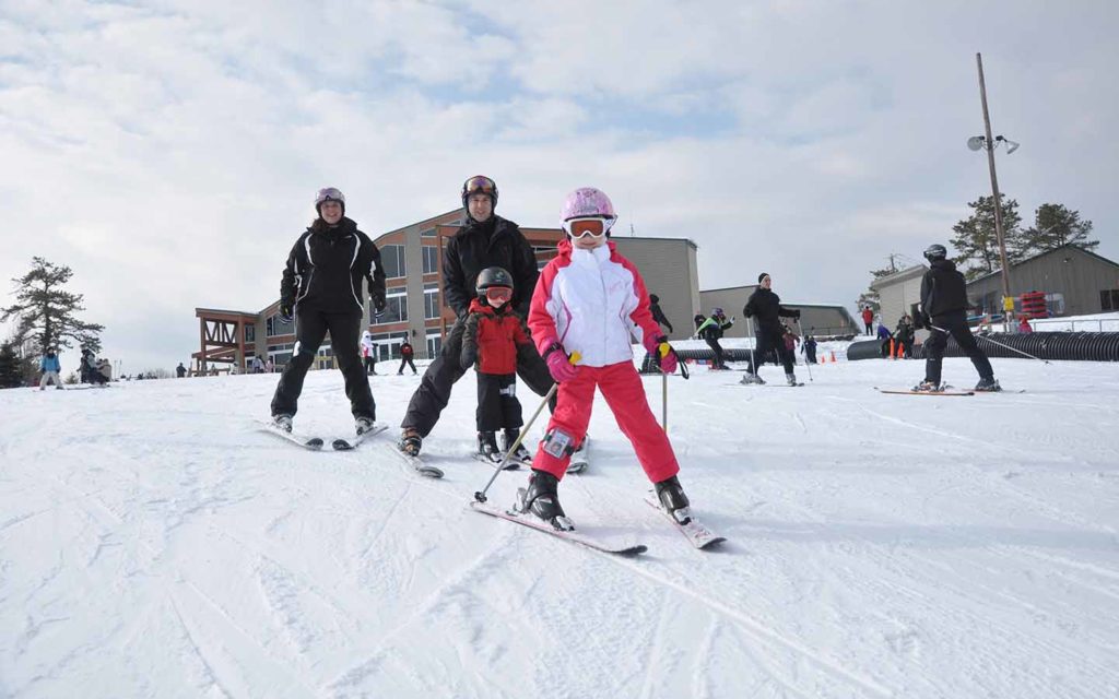 Children and adults skiing on beginner hill.
