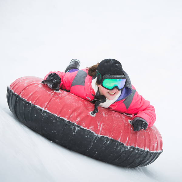 Young girl sledding downhill on an inner tube.