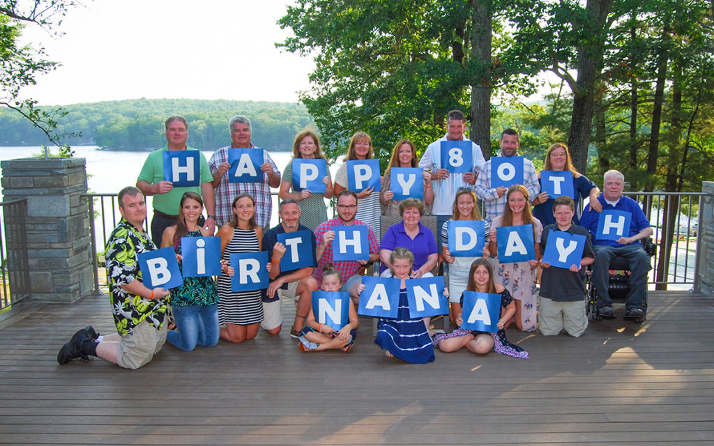 Family Reunion photo with each family member holding a letter of the alphabet. Text: Happy 80th Birthday, Nana.