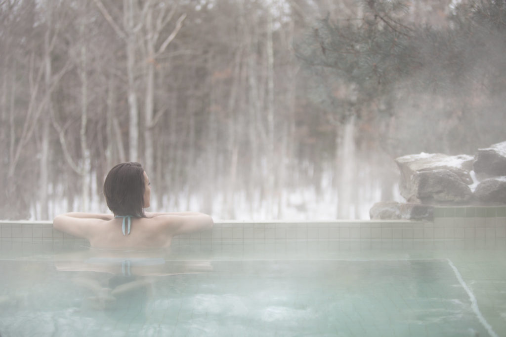 Woman sitting in outdoor hot tub in winter.