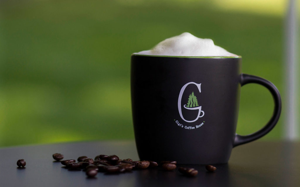 Coffee mug with foam and loose beans around the mug.