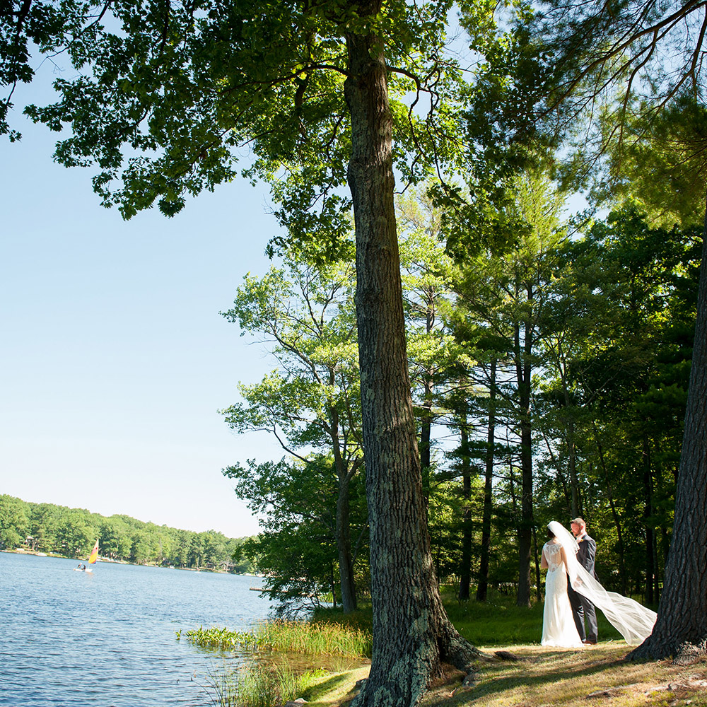 Bride and Groom standing by lake.