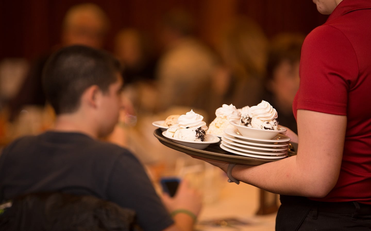 Server with a tray of ice cream desserts.